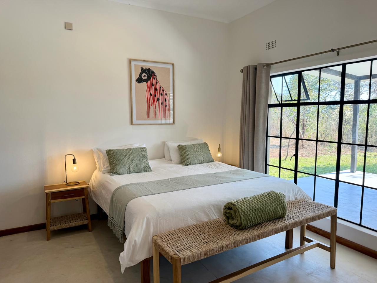 The double bedroom at Marula Cottage, with sage-green bedding and a garden window